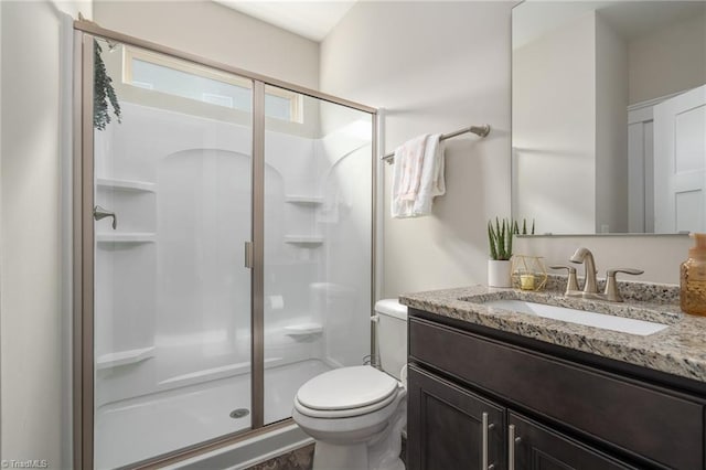 full bath with vanity, a shower stall, and toilet