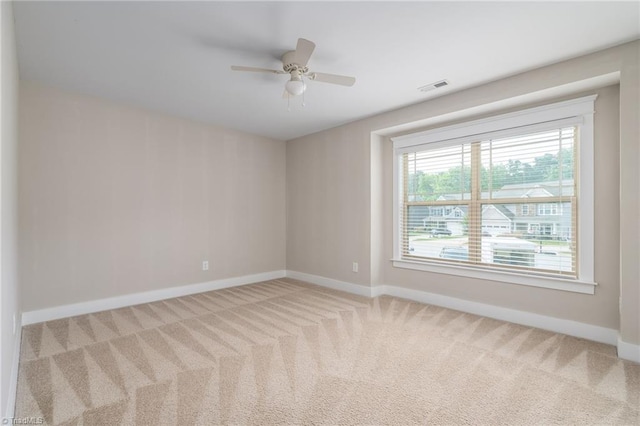 empty room featuring visible vents, baseboards, ceiling fan, and light colored carpet
