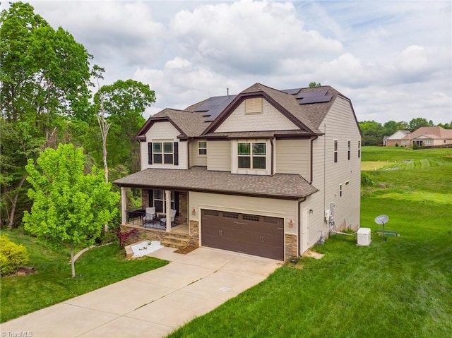 craftsman-style home with a porch, driveway, a front yard, roof mounted solar panels, and an attached garage