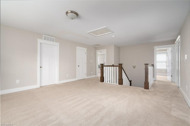 spare room with light colored carpet, baseboards, visible vents, and attic access