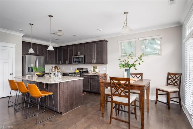 kitchen with ornamental molding, dark brown cabinets, dark wood finished floors, appliances with stainless steel finishes, and backsplash