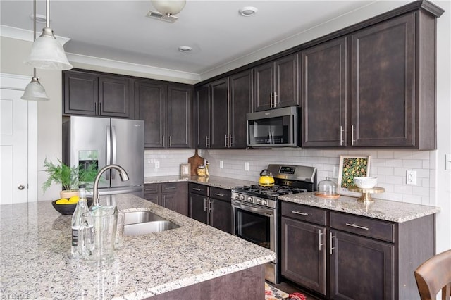 kitchen featuring visible vents, appliances with stainless steel finishes, dark brown cabinets, a sink, and light stone counters