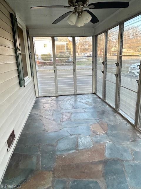 unfurnished sunroom with visible vents and a ceiling fan