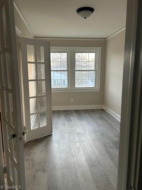 interior space featuring baseboards, wood finished floors, and crown molding