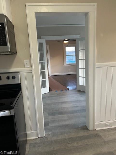 interior space with wainscoting, appliances with stainless steel finishes, ceiling fan, and wood finished floors