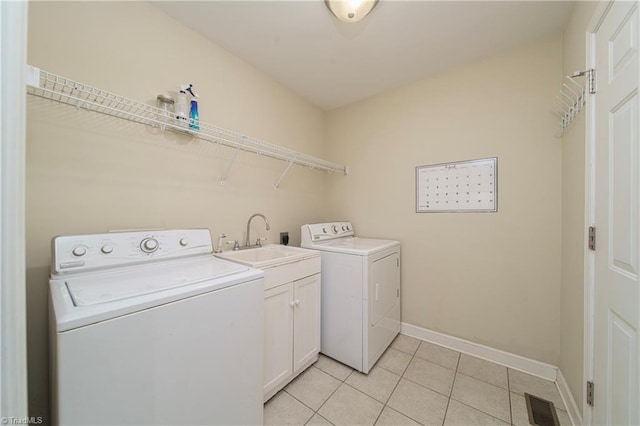 laundry room featuring light tile patterned floors, cabinets, sink, and washing machine and dryer