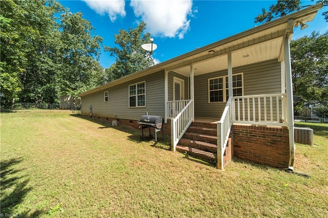 rear view of property with a lawn and cooling unit