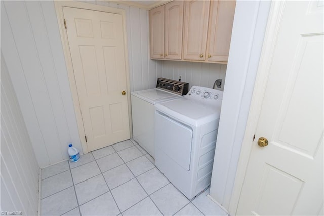 laundry room with cabinets, light tile patterned floors, washer and dryer, and wood walls