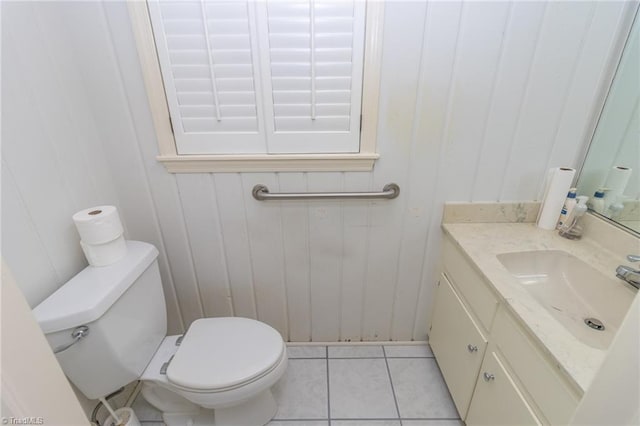 bathroom featuring toilet, vanity, tile patterned floors, and wood walls