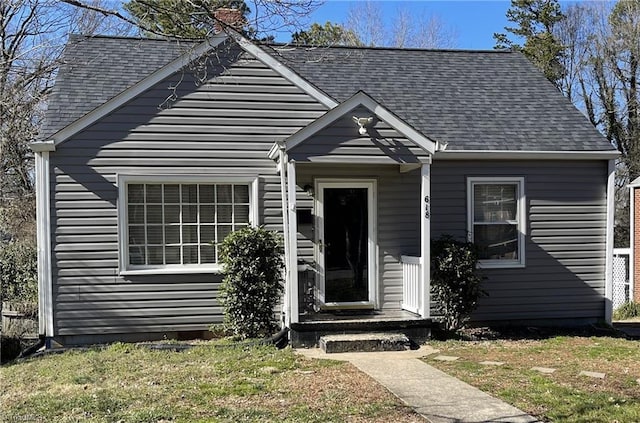 bungalow-style home with a front yard and roof with shingles