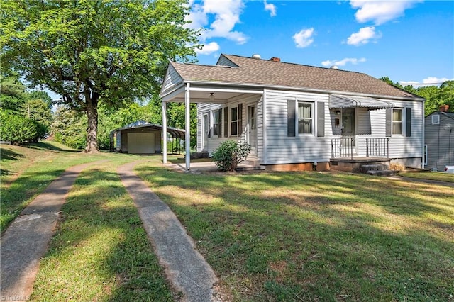 bungalow with an outbuilding, a front yard, and a shingled roof