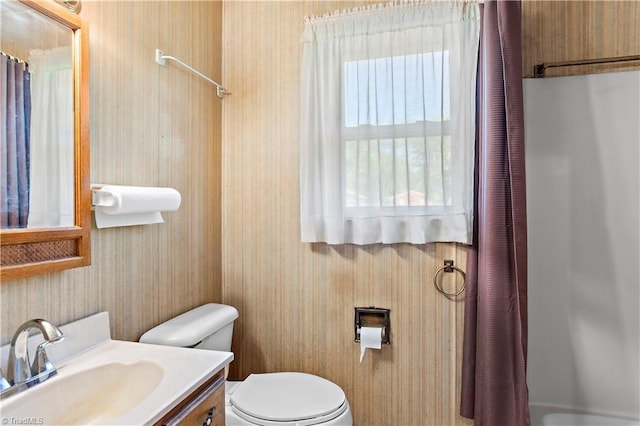 bathroom with wallpapered walls, toilet, vanity, and a shower with curtain