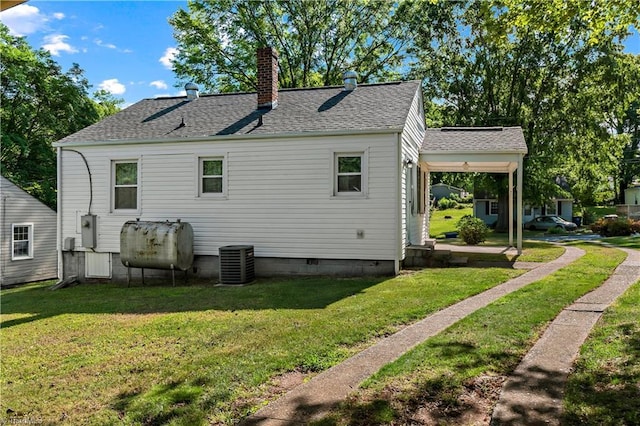 back of property featuring oil tank, roof with shingles, a chimney, and a lawn