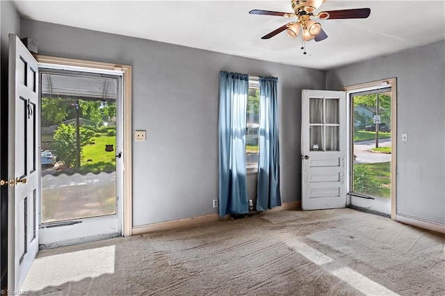 entryway with healthy amount of natural light, carpet, baseboards, and ceiling fan