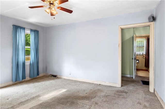 carpeted spare room featuring baseboards and ceiling fan