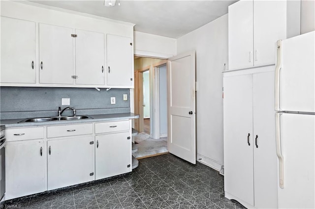 kitchen with freestanding refrigerator, a sink, dark floors, white cabinetry, and light countertops