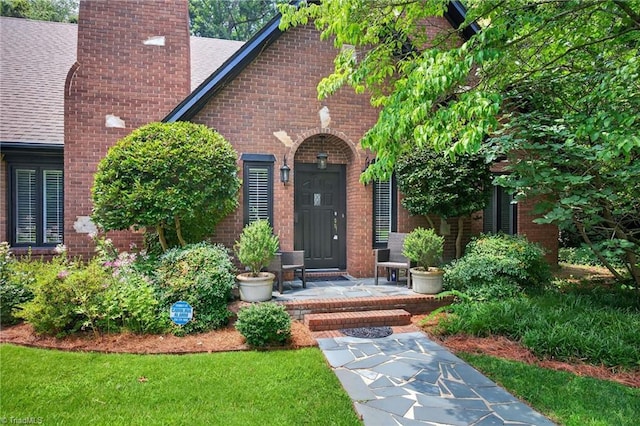 1901 Runnymede Rd, Winston-Salem, NC 27104 - property entrance featuring a chimney, brick siding, a shingled roof, and a porch