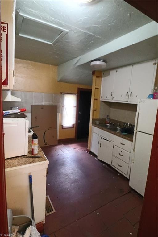 kitchen with white refrigerator and white cabinets