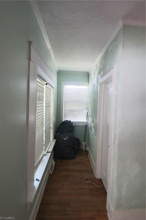 hallway with dark hardwood / wood-style flooring, crown molding, and a textured ceiling