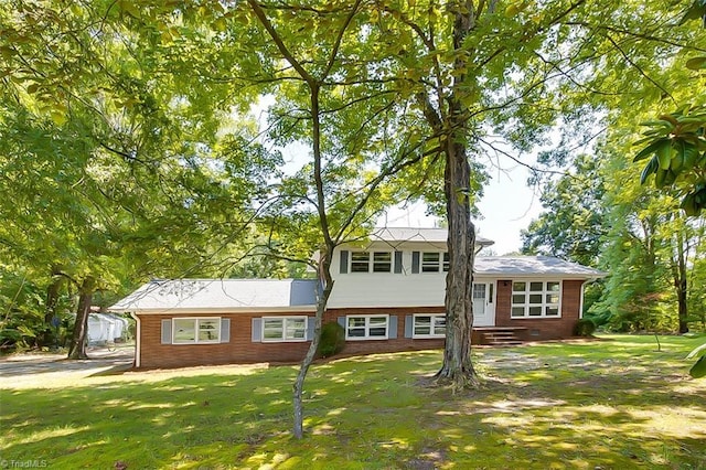 tri-level home featuring crawl space, entry steps, brick siding, and a front yard