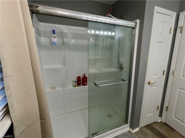 bathroom with wood-type flooring and a shower with door