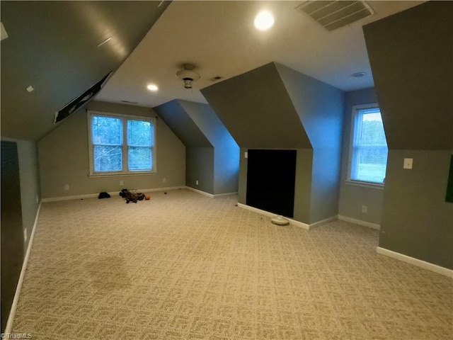 additional living space featuring plenty of natural light, light colored carpet, and lofted ceiling