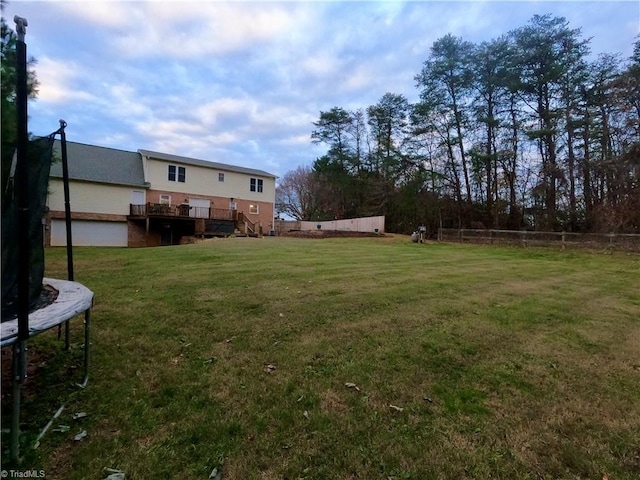 view of yard with a trampoline and a wooden deck