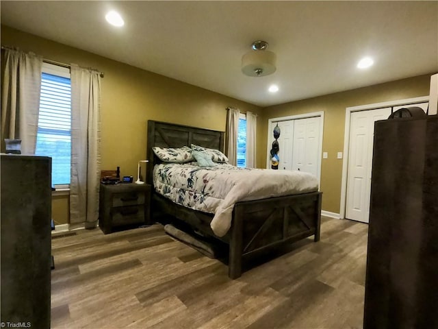 bedroom with dark hardwood / wood-style floors and multiple closets