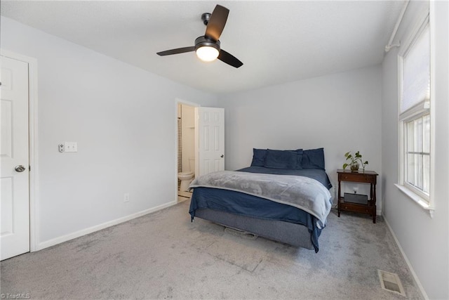 carpeted bedroom with visible vents, connected bathroom, baseboards, and ceiling fan