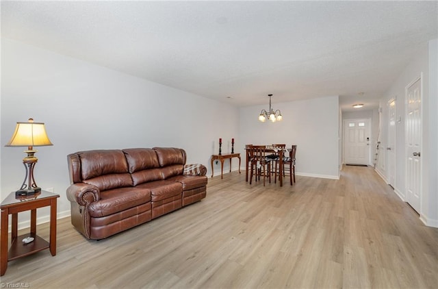 living room featuring light wood-style floors, baseboards, and a notable chandelier