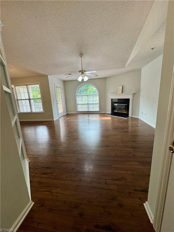733 Rivertree Ln, Winston-Salem, NC 27103 - unfurnished living room with a textured ceiling, healthy amount of natural light, dark wood-type flooring, and ceiling fan