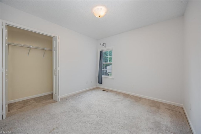 unfurnished bedroom featuring light carpet and a closet