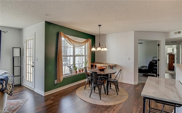 dining area featuring a chandelier, a textured ceiling, and dark hardwood / wood-style flooring