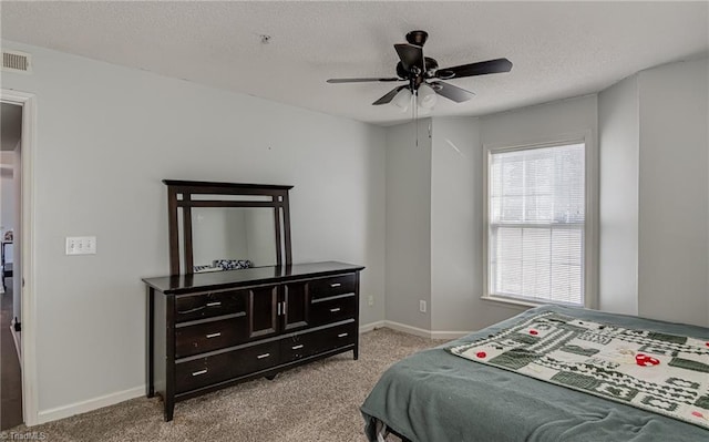 bedroom with ceiling fan, light carpet, and a textured ceiling