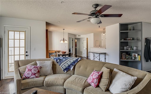 living room with ceiling fan with notable chandelier, wood-type flooring, and a textured ceiling