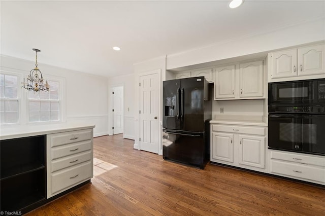 kitchen with dark hardwood / wood-style floors, pendant lighting, white cabinets, a chandelier, and black appliances