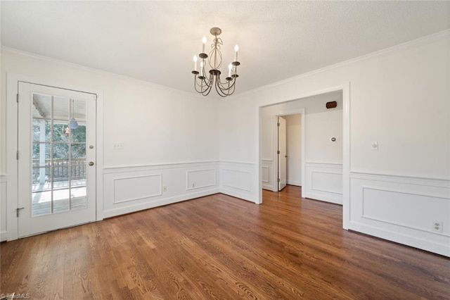 unfurnished dining area with dark wood-type flooring, ornamental molding, and a notable chandelier