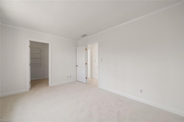 unfurnished bedroom featuring a walk in closet, light colored carpet, and a closet