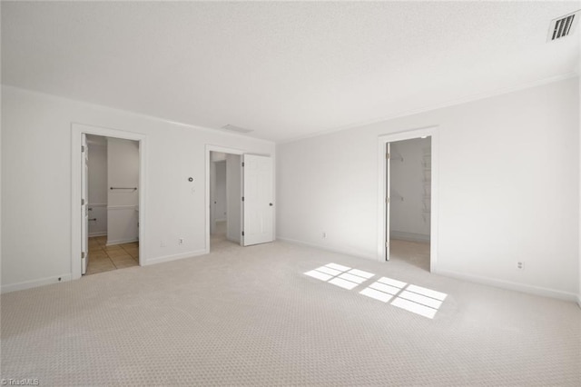 unfurnished bedroom featuring a closet, connected bathroom, a spacious closet, and light carpet