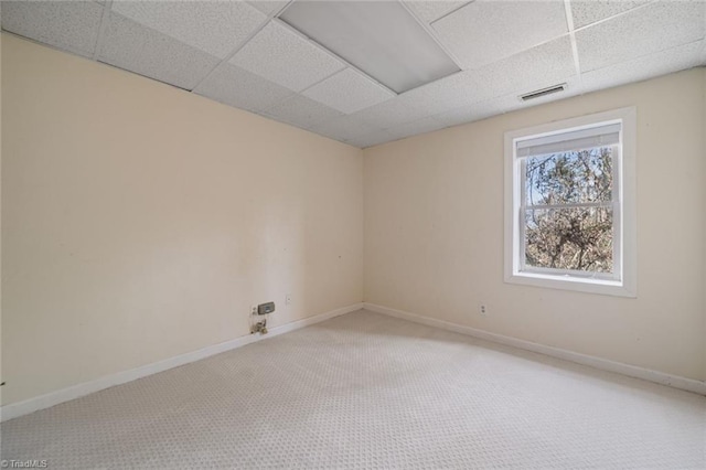 carpeted spare room with a drop ceiling