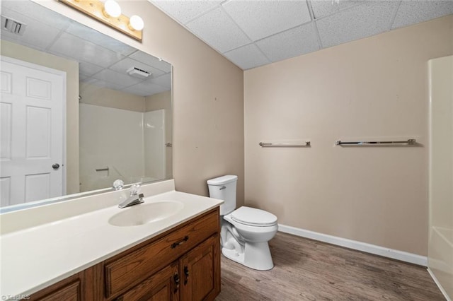 bathroom with hardwood / wood-style flooring, vanity, a drop ceiling, and toilet