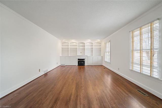 unfurnished living room featuring crown molding, dark wood-type flooring, built in features, and a textured ceiling