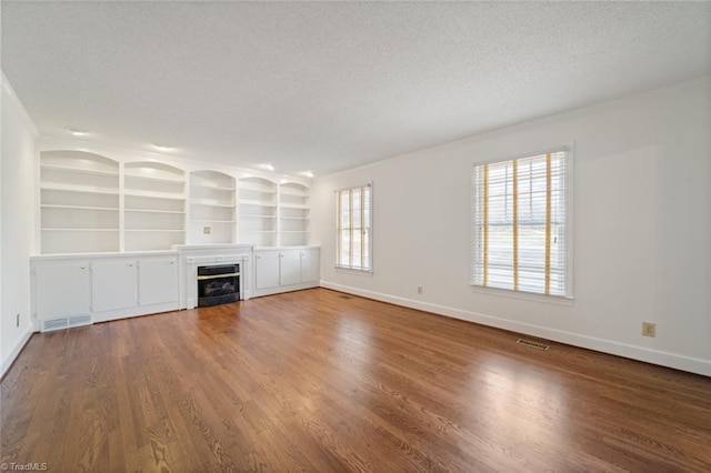 unfurnished living room with hardwood / wood-style flooring, built in features, and a textured ceiling