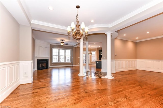 unfurnished living room with ornate columns, ornamental molding, and wood-type flooring