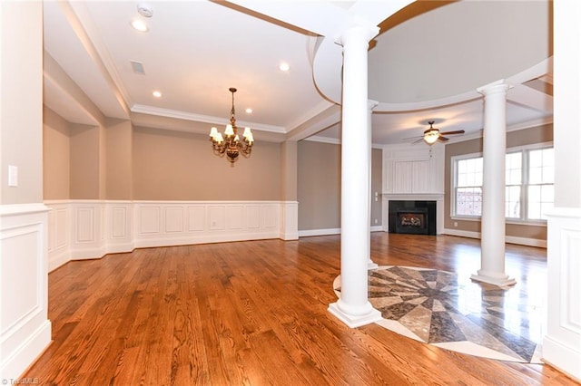 unfurnished living room with ornate columns, ornamental molding, wood-type flooring, and ceiling fan