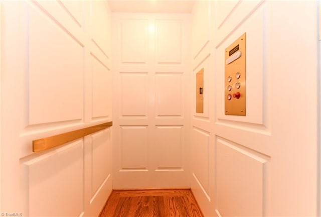 hall with hardwood / wood-style flooring and elevator