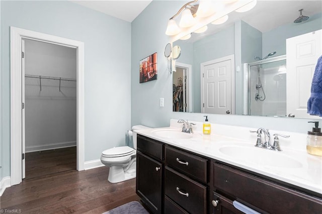 bathroom with wood finished floors, toilet, a sink, and a stall shower