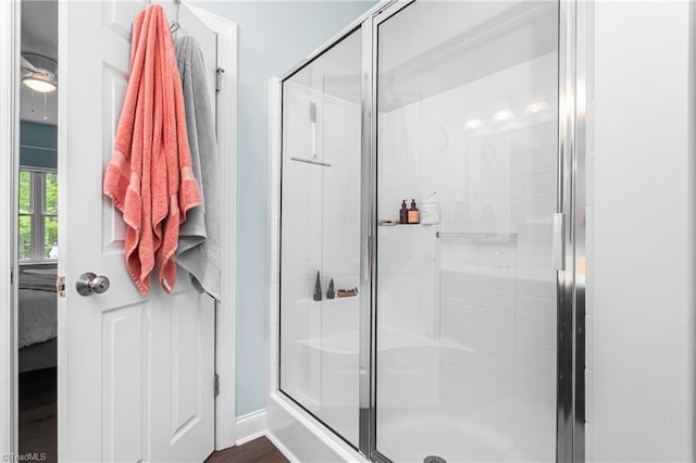 ensuite bathroom featuring baseboards, a shower stall, and connected bathroom