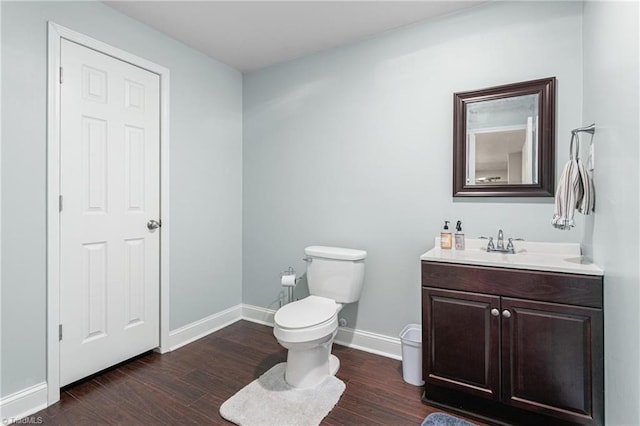 half bathroom featuring baseboards, wood finished floors, toilet, and vanity