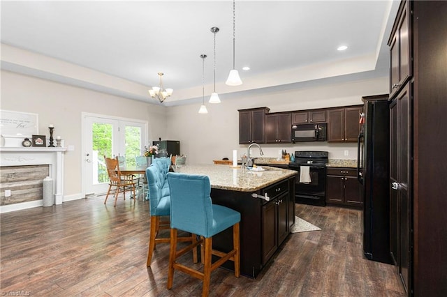 kitchen with an inviting chandelier, a raised ceiling, black appliances, and dark wood-style floors